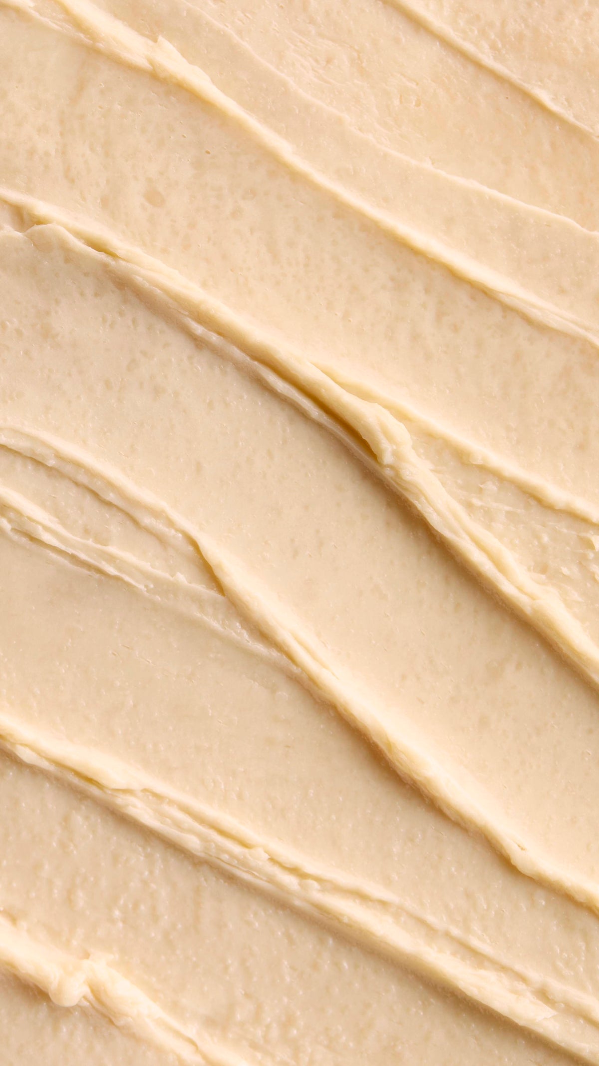 A close-up of a Super Milk Shampoo with distinct, diagonal ridges and soft peaks. The texture suggests a rich, thick consistency, creating a visually pleasing and inviting pattern of smooth swirls.